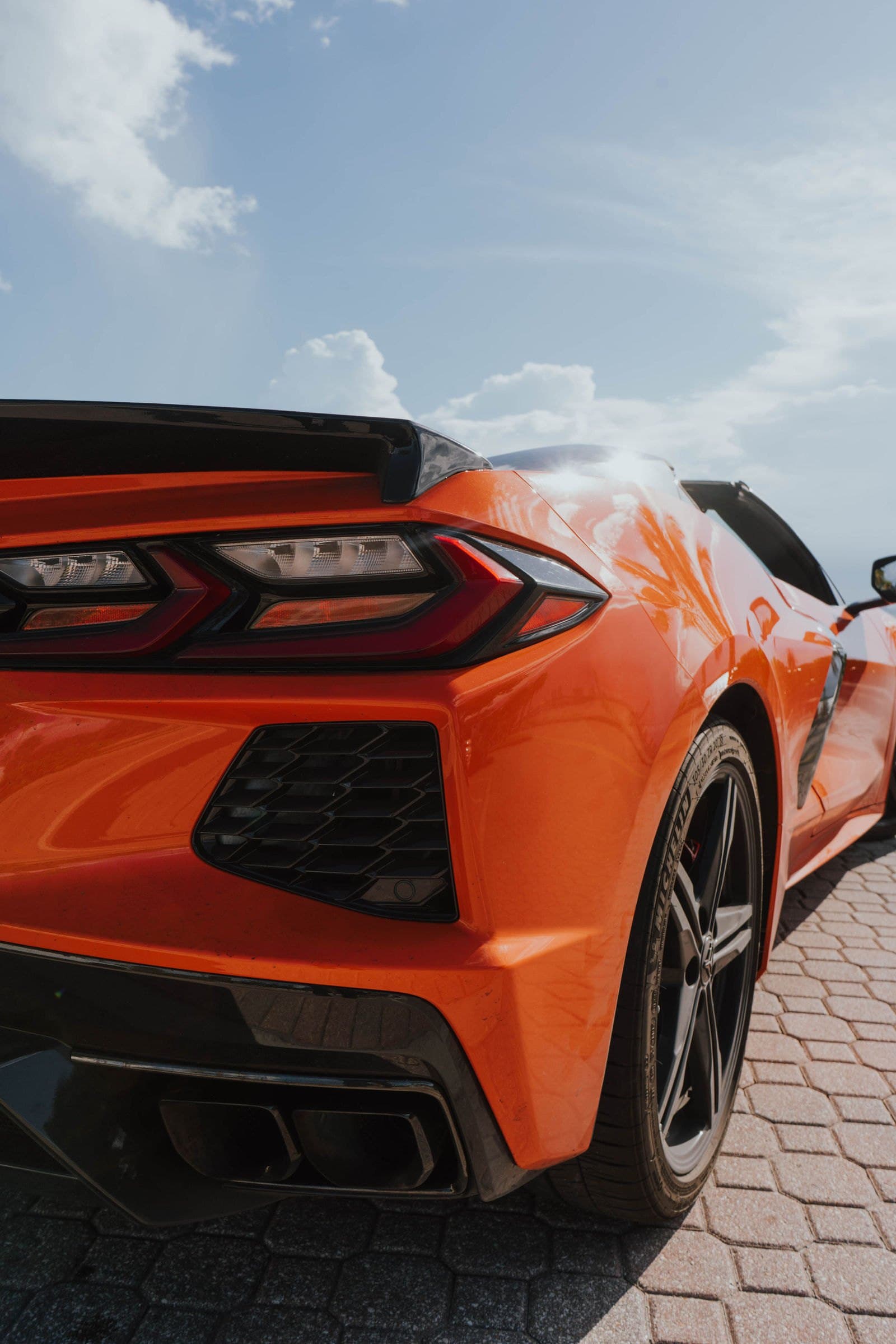 Black wheel and taillight of an orange Corvette C8