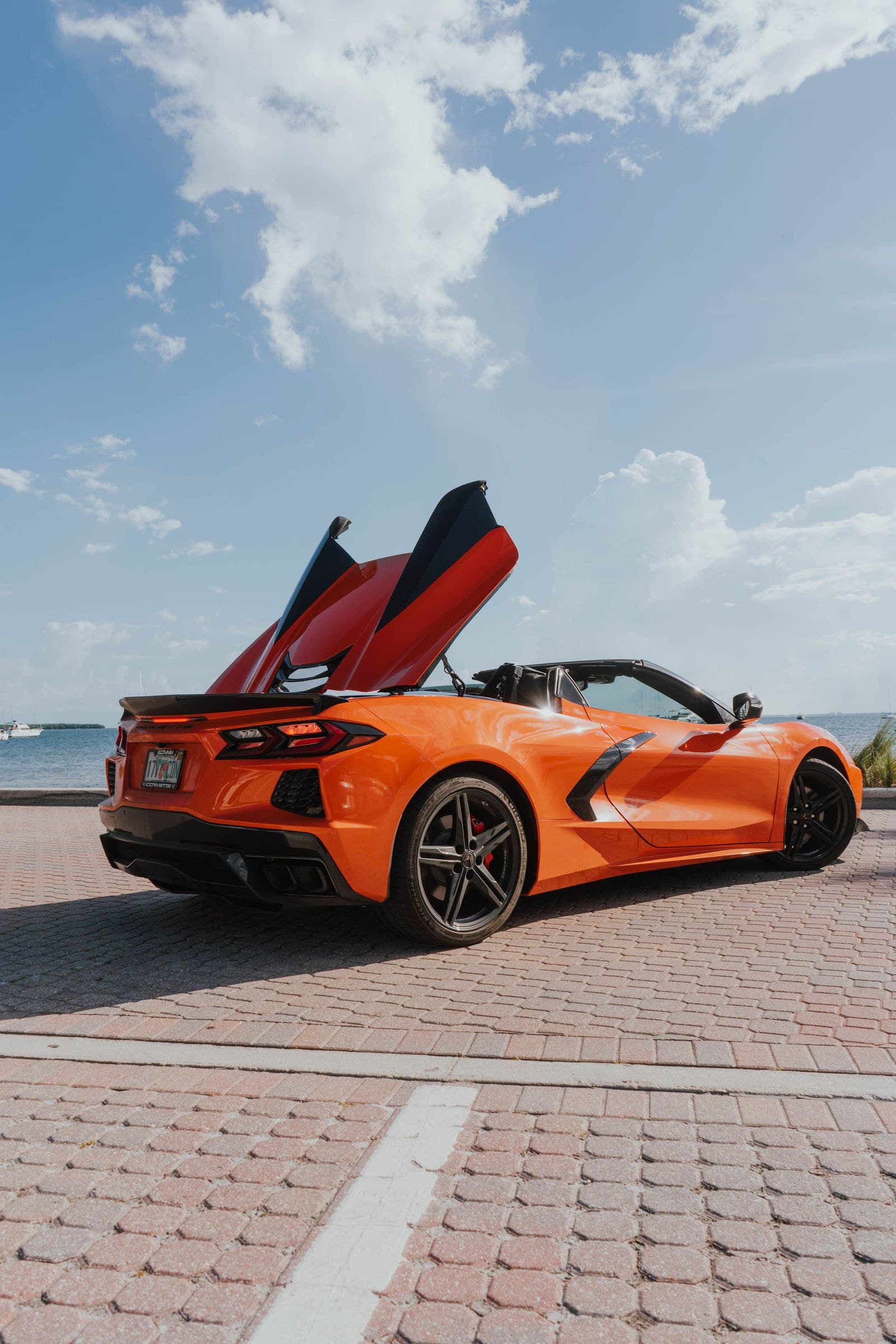 Orange Corvette C8 convertible with the hood raised by the bay
