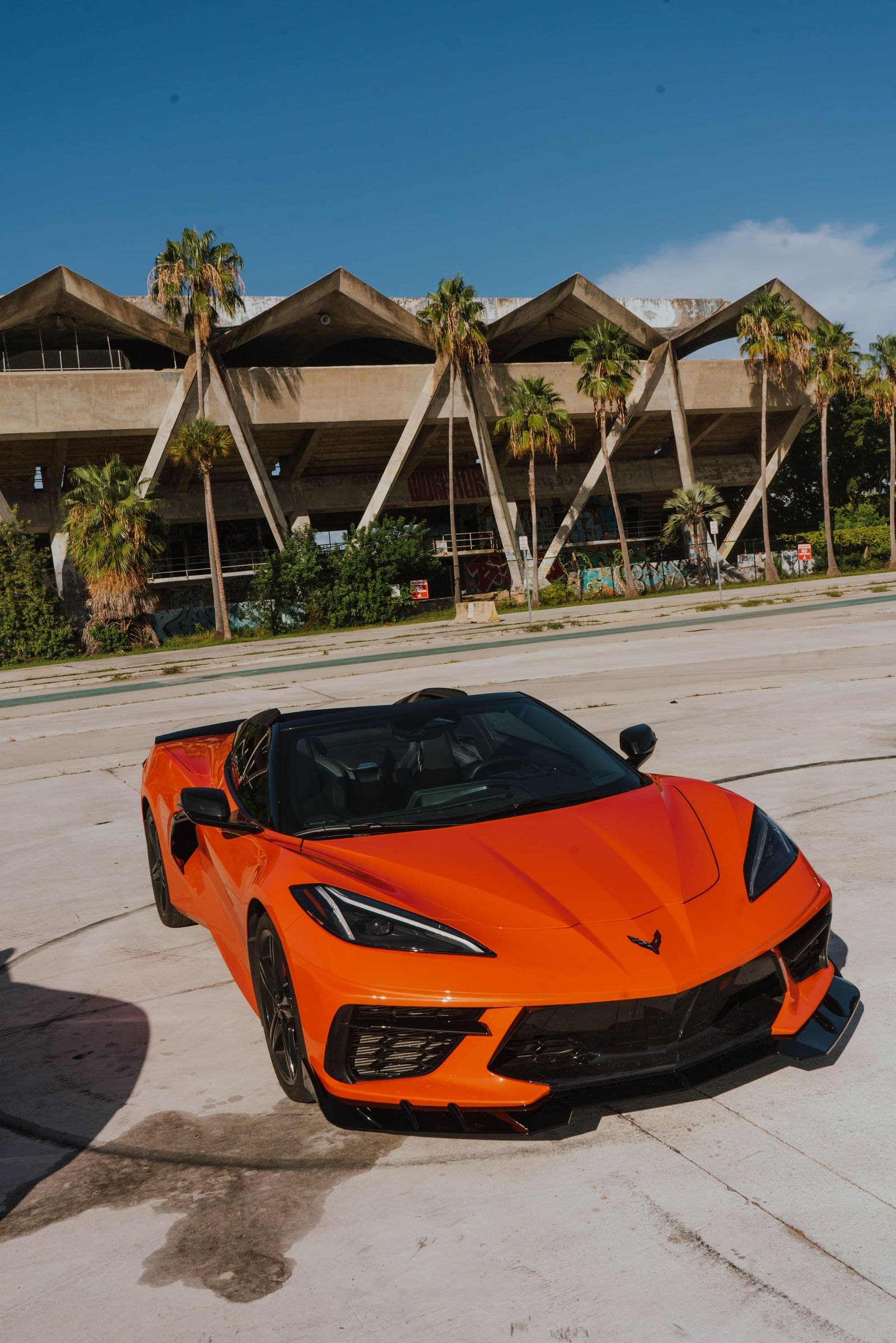 Orange Corvette C8 in front of the Miami Marine Stadium