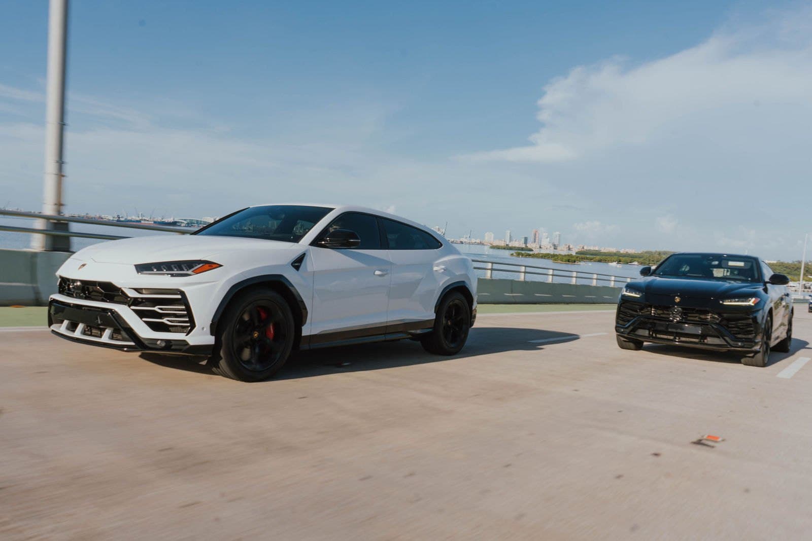 Two Lamborghini Urus SUVs driving on the Miami causeway