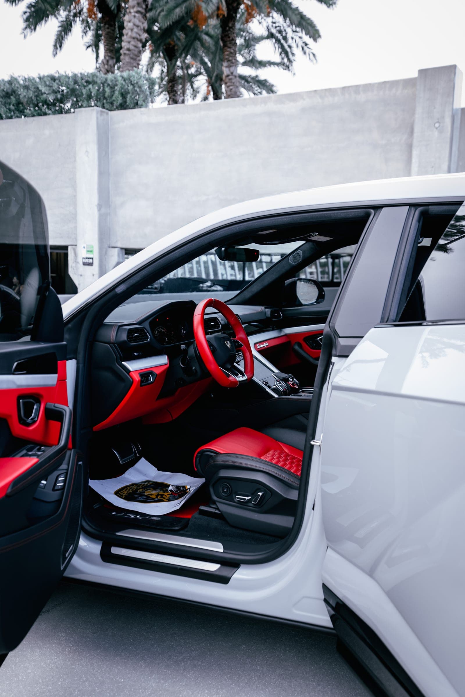 Red leather interior of a grey Lamborghini Urus with the door open